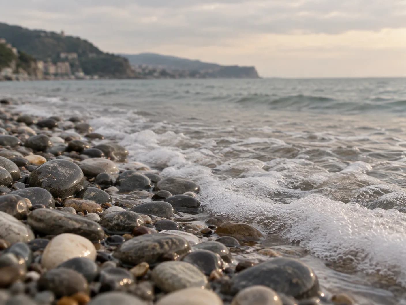 Karadeniz sahilinde ıslak gri deniz taşları ve köpüklü dalga kenarı, yumuşak sabah ışığı