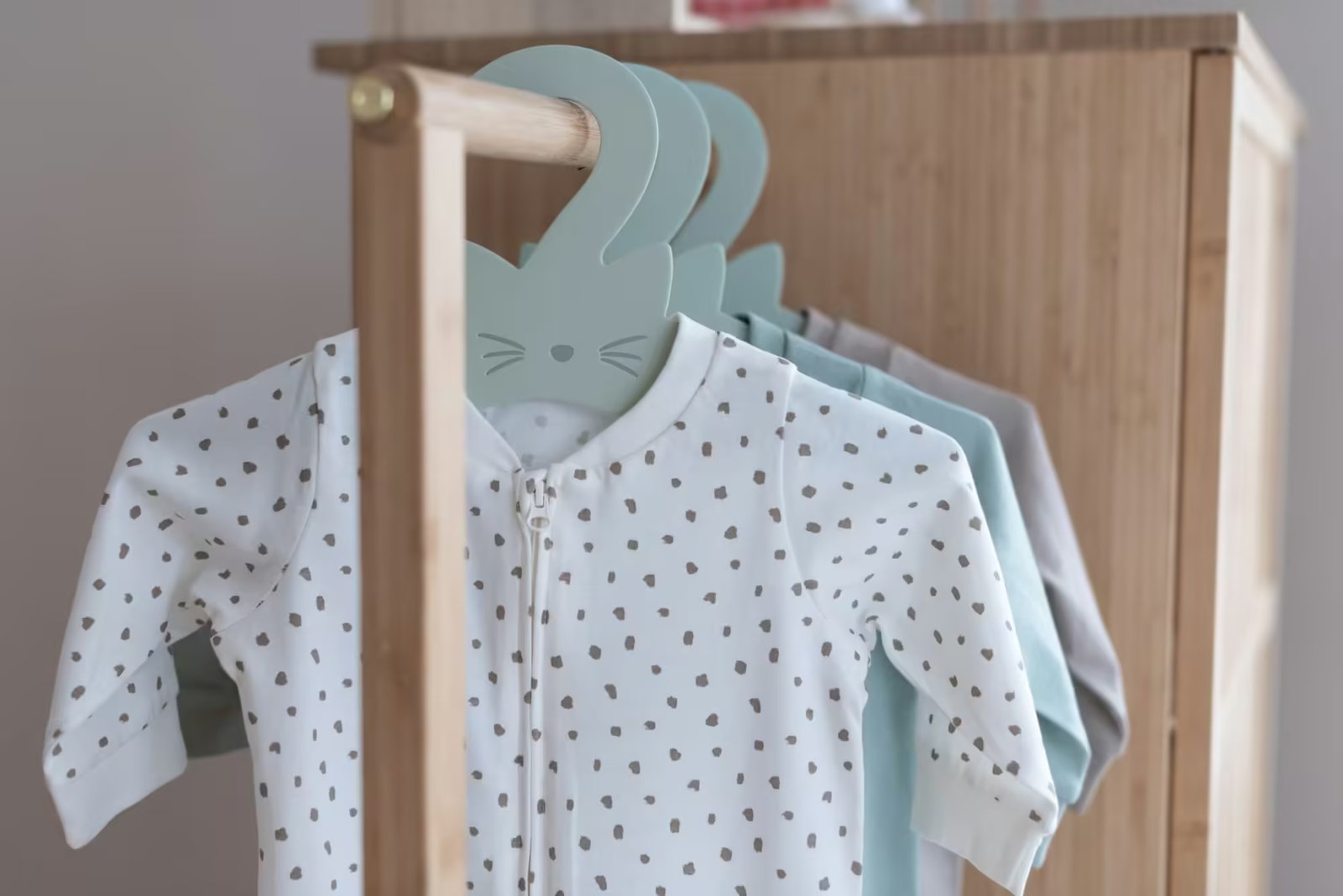 Set of cute bodysuits for newborn on hangers.